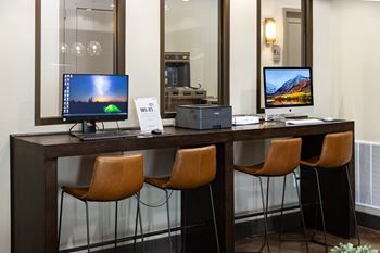 A modern workspace with two computers and three chairs.
